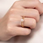 Gros plan de la bague ajustable Ondée en plaqué or 3 microns avec une perle de culture blanche, portée sur une main.
