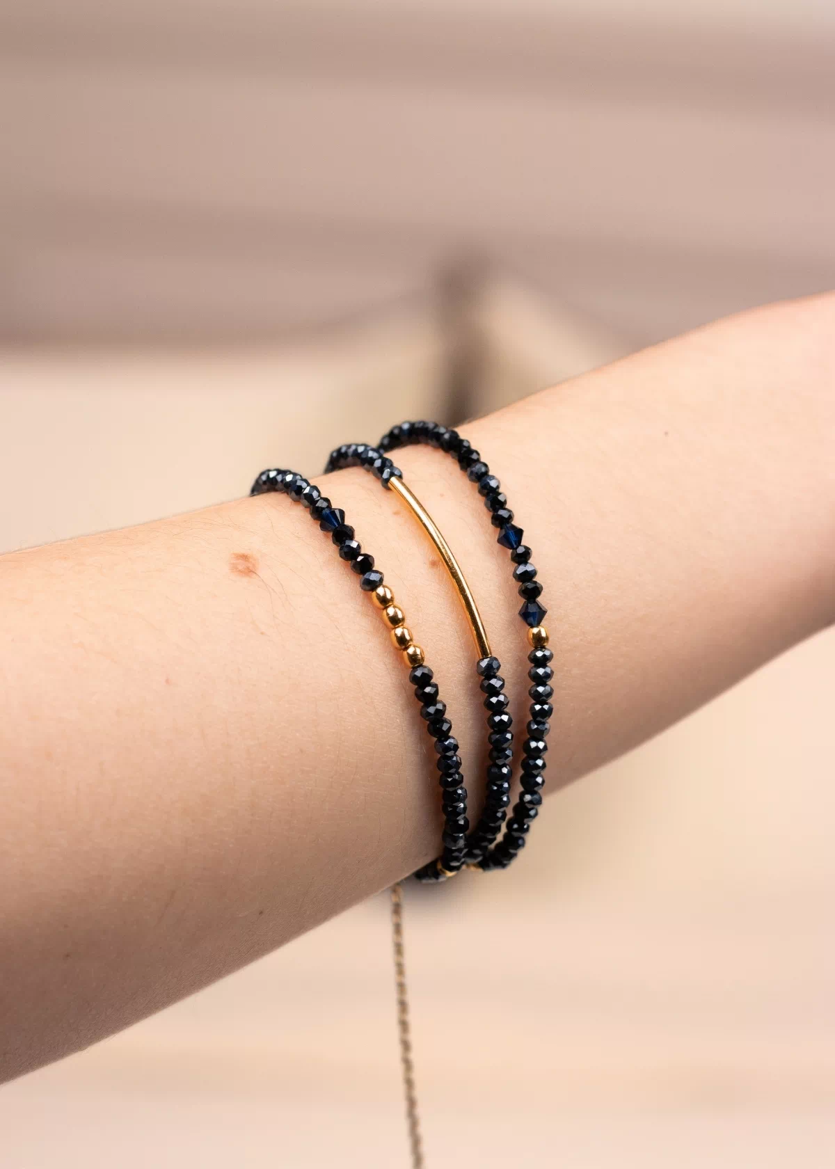 Gros plan du bracelet Nocturne enroulé trois fois autour du poignet, avec des perles facettées bleu marine, des détails dorés et une chaîne d'extension
