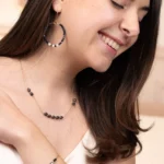 Créole Éclat portée à l'oreille, avec des perles facettées bleu marine et des perles de culture blanches, sur un modèle aux cheveux bruns.