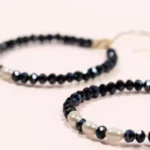 Gros plan des créoles Éclat en or laminé 14 carats, ornées de perles de Bohême bleu marine et de perles de culture blanches.