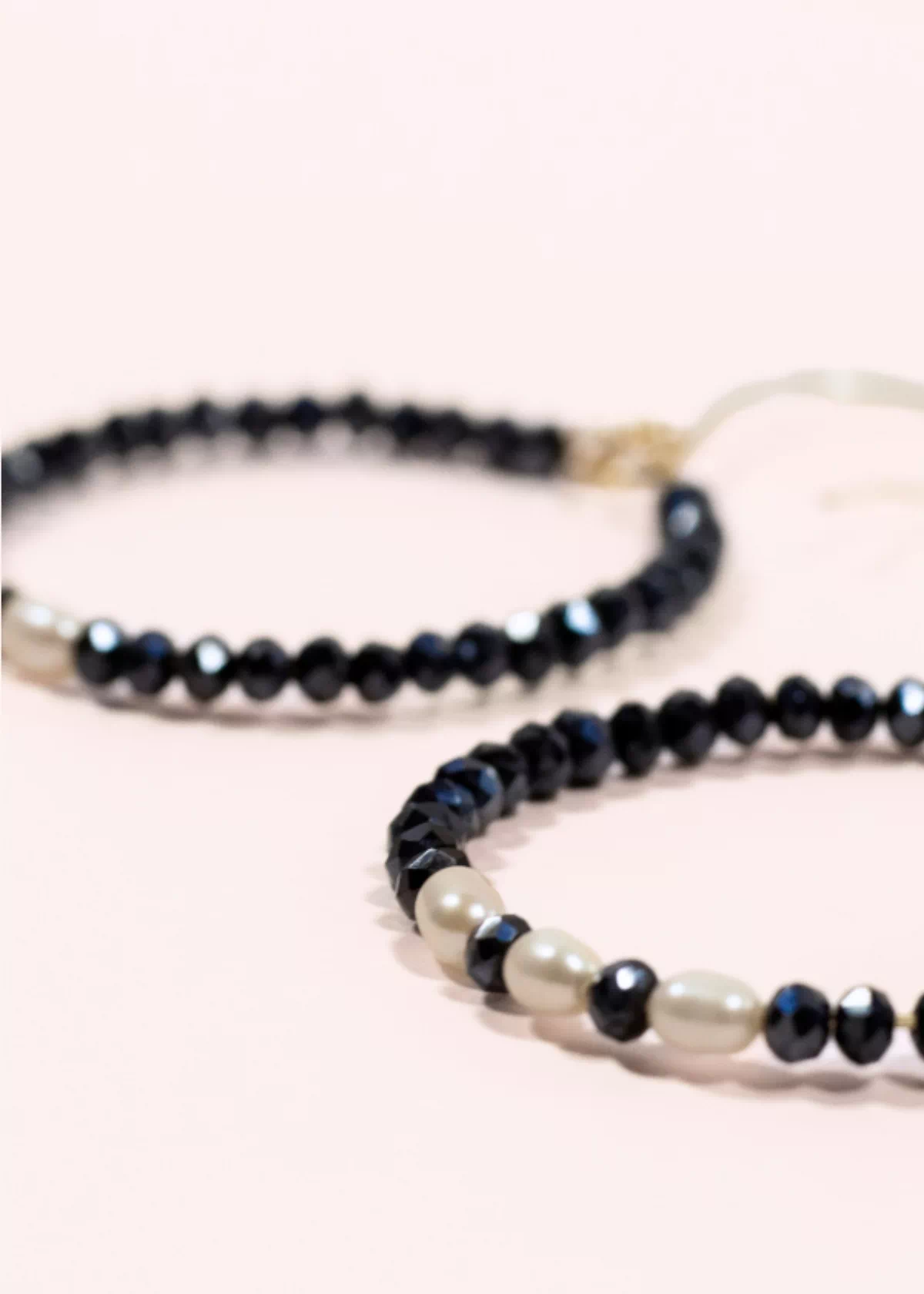 Gros plan des créoles Éclat en or laminé 14 carats, ornées de perles de Bohême bleu marine et de perles de culture blanches.