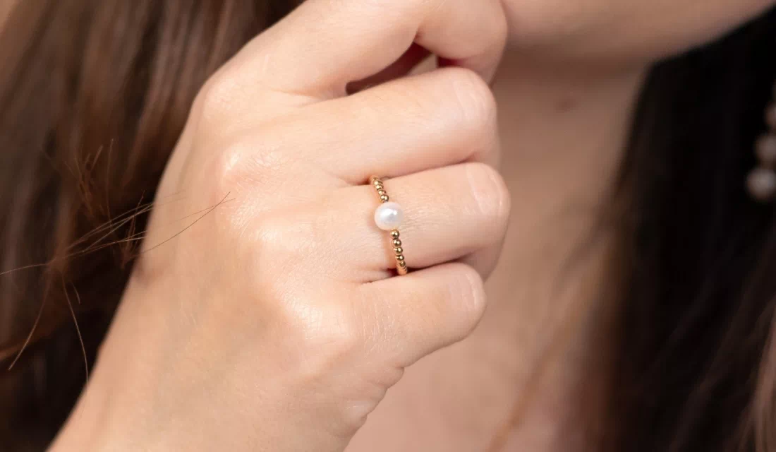 Femme portant une bague dorée avec perle