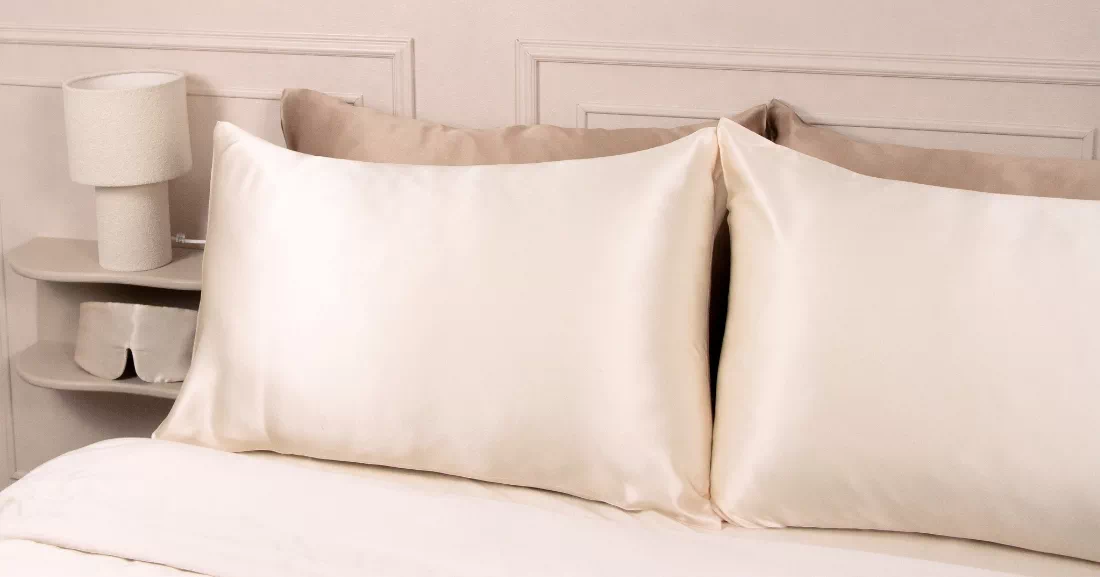 Deux taies d’oreiller en soie champagne sur un lit