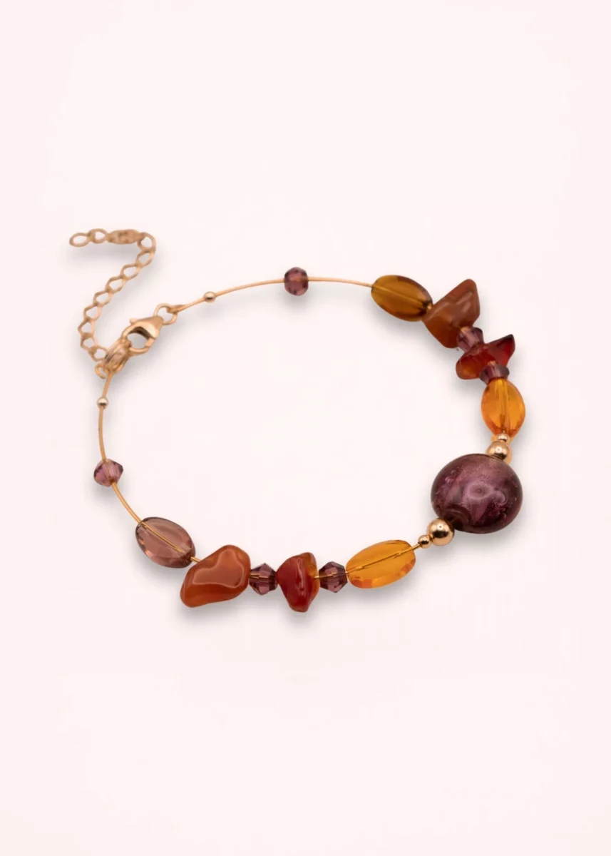 Bracelet Delphéa en pierres naturelles de cornaline et d'agate rouge-orange, avec perle violette en verre de Bohême, détails Swarovski et or laminé 14K, sur fond clair.