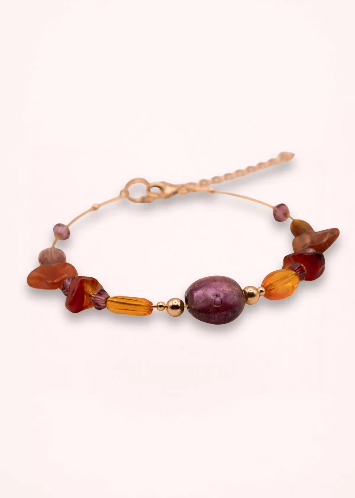 Vue rapprochée du bracelet Delphéa avec sa grande perle violette en verre de Bohême, ses pierres de cornaline et d'agate rouge-orange et ses détails dorés.