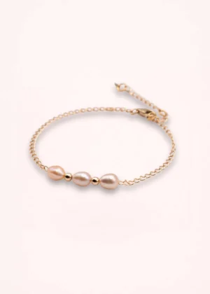 Bracelet Esmée en perles d'eau douce blanches aux reflets nacrés, avec chaîne fine et détails dorés en or laminé 14 carats, sur fond clair.