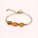 Vue rapprochée du bracelet Marélie montrant ses perles en verre de Bohême orange et jaune doré, sa chaîne fine en or laminé et son pendentif feuille dorée.