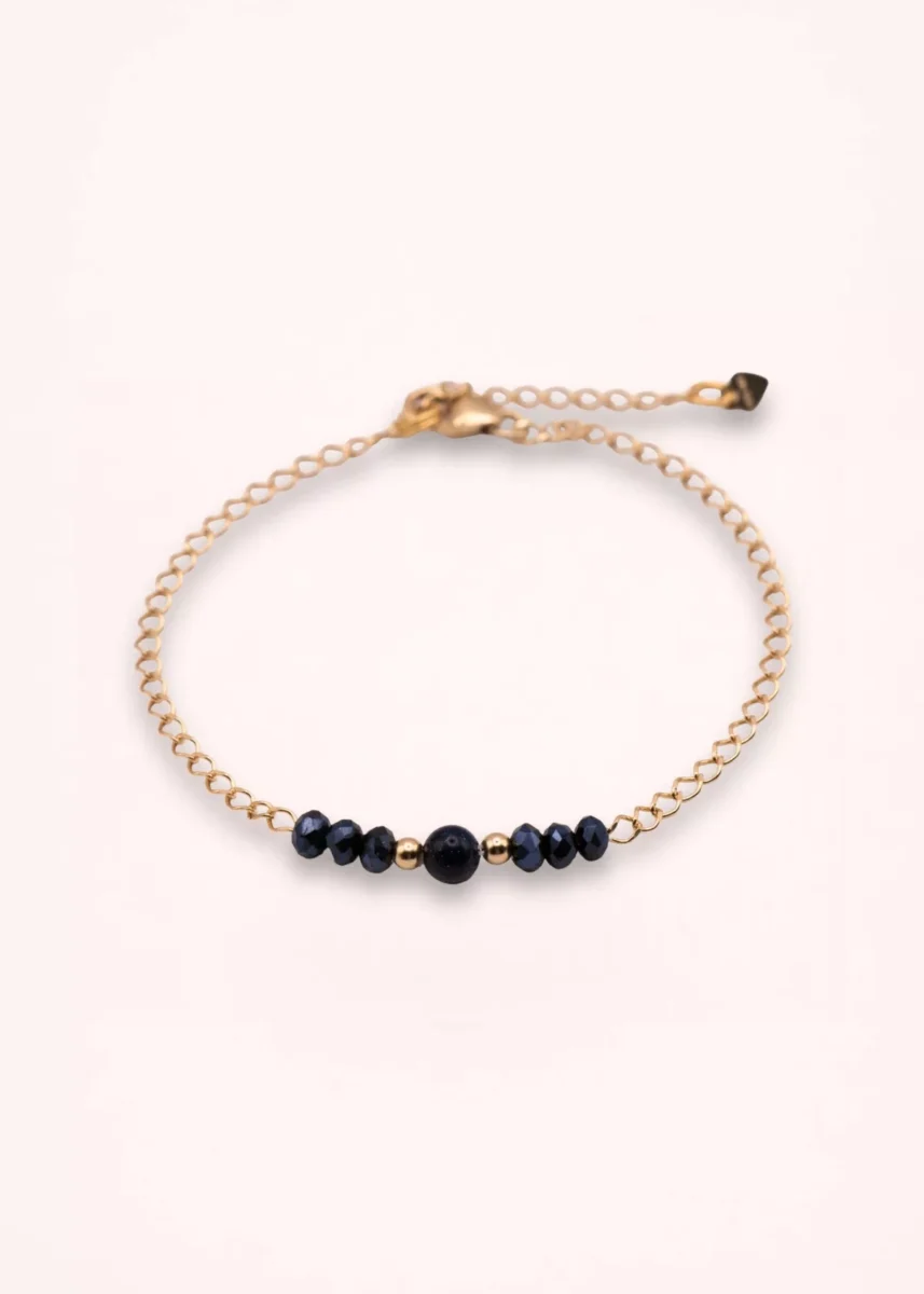 Bracelet Nalia en or laminé 14 carats avec perles bleu nuit en verre de Bohême, détail central en goldstone bleu et chaîne fine ajustable, sur fond clair.