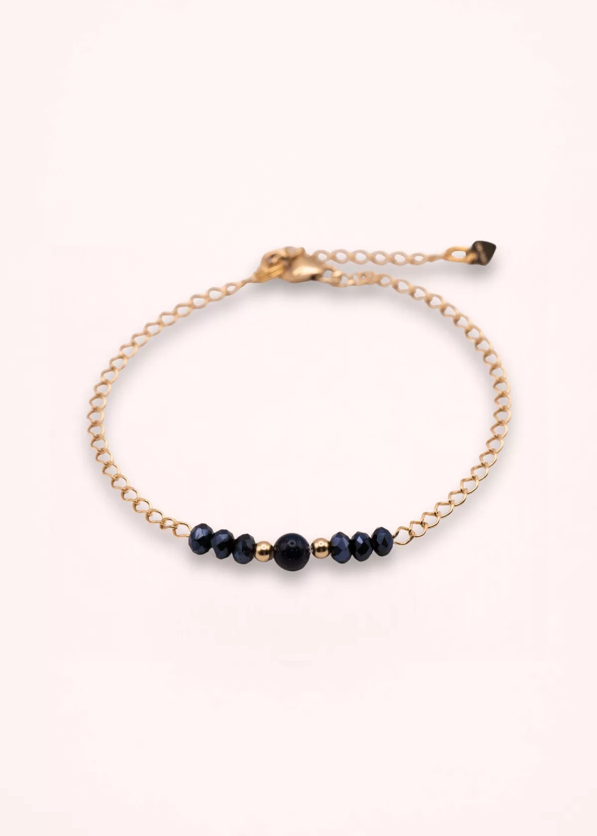 Bracelet Nalia en or laminé 14 carats avec perles bleu nuit en verre de Bohême, détail central en goldstone bleu et chaîne fine ajustable, sur fond clair.
