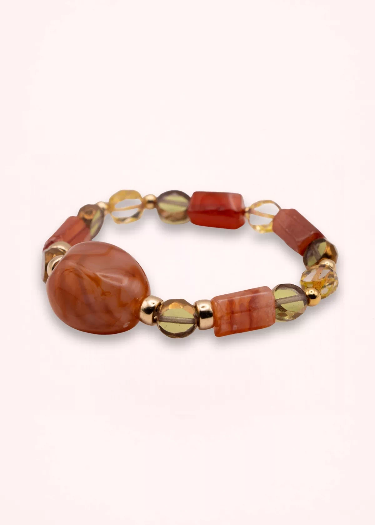 Vue rapprochée du bracelet Sienna montrant sa grande perle centrale en verre de Bohême, ses pierres de cornaline orange et ses perles dorées en or laminé.
