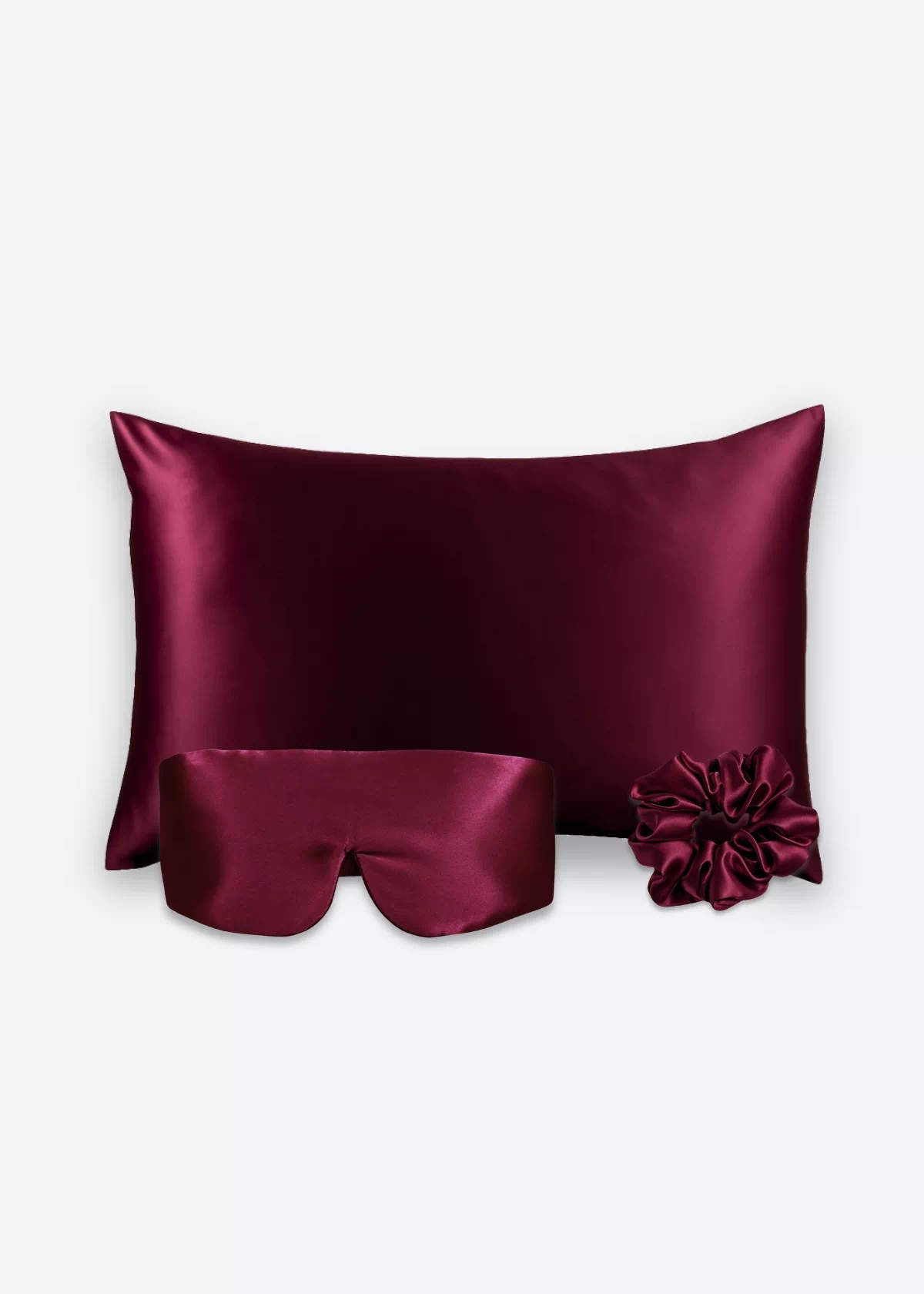 Coffret Les Essentiels Bandeau : taie d’oreiller, masque bandeau réglable et grand chouchou, tous en soie bordeaux.