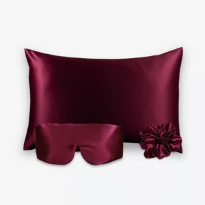 Coffret Les Essentiels Bandeau : taie d’oreiller, masque bandeau réglable et grand chouchou, tous en soie bordeaux.