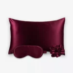 Coffret Les Essentiels : taie d’oreiller, masque de nuit classique et grand chouchou, tous en soie bordeaux.