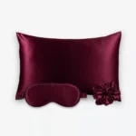 Coffret Les Essentiels : taie d’oreiller, masque de nuit classique et grand chouchou, tous en soie bordeaux.