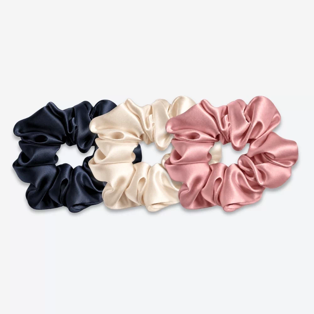Trois grands chouchous en soie : un bleu nuit, un champagne et un bois de rose.