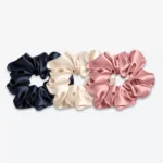 Trois grands chouchous en soie : un bleu nuit, un champagne et un bois de rose.
