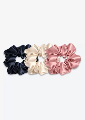 Trois grands chouchous en soie : un bleu nuit, un champagne et un bois de rose.