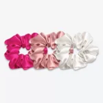 Trois grands chouchous en soie : un rose fuchsia, un bois de rose et un blanc crème.