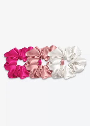 Trois grands chouchous en soie : un rose fuchsia, un bois de rose et un blanc crème.